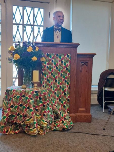 Rev. Duncan Teague standing behind a decorated pulpit.